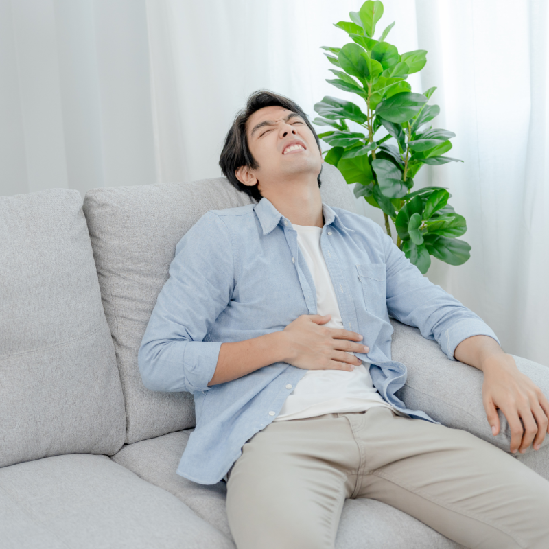 man lying on a couch suffering from incontinence pain